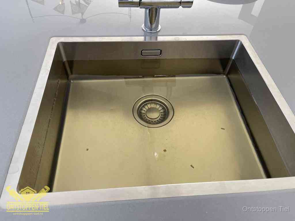 Stilstaand water in een rvs spoelbak dat niet wegloopt, een duidelijk signaal van een gootsteenverstopping in Tiel
