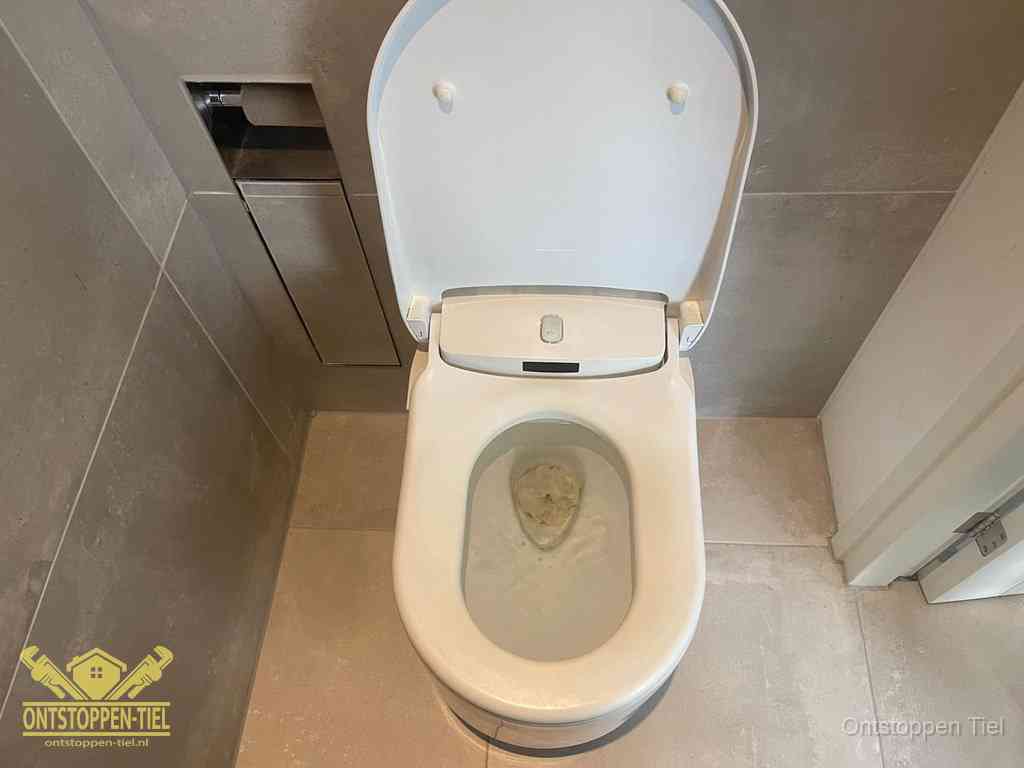 Een wit hangtoilet waarin een prop wc-papier op het water blijft drijven, een duidelijk signaal van een verstopte wc in Tiel