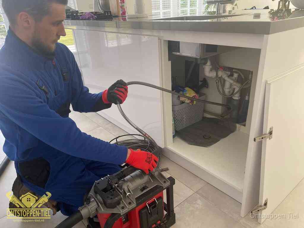 Een monteur reinigt de keukenafvoer grondig met een veermachine om terugkerende gootsteenverstoppingen te voorkomen in Tiel