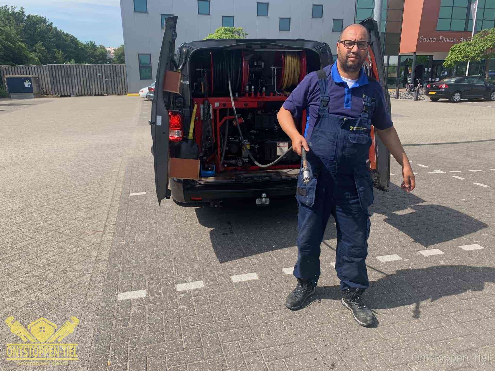 Een monteur bij zijn bestelbus met een hogedruk- en rioolreinigingsunit, klaar om de oorzaak van terugkerende wc-verstoppingen aan te pakken in Tiel