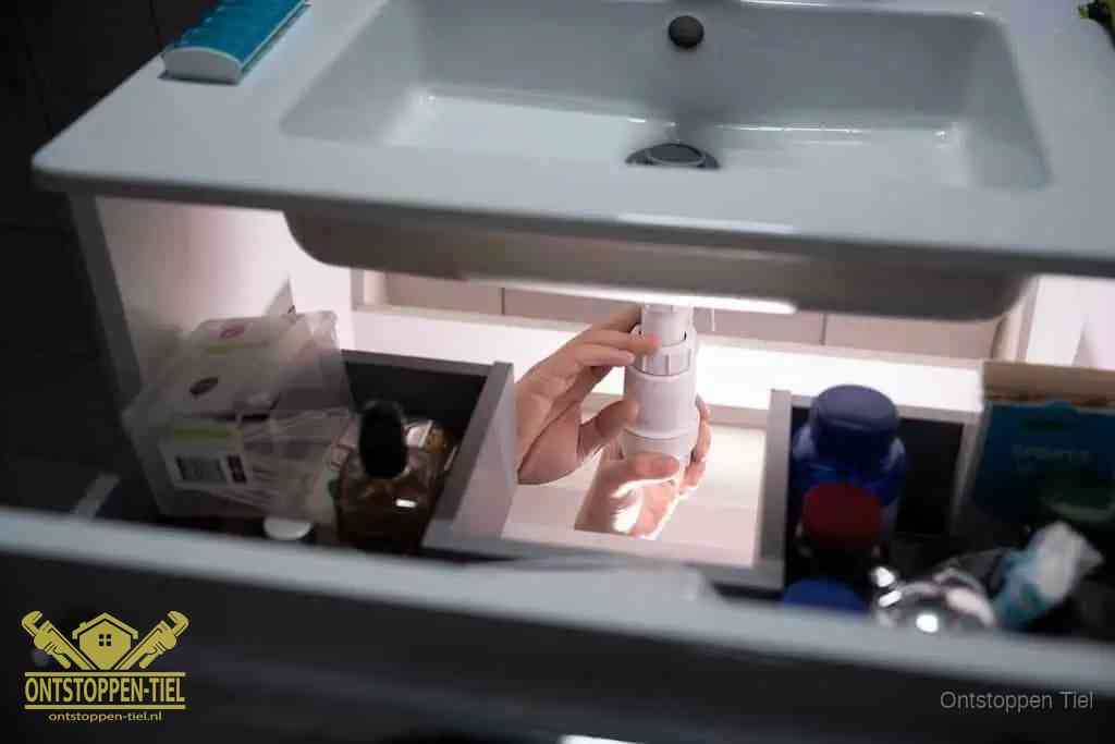 Een pompfles met zeep boven een wastafel in de toiletruimte, de warm water en afwasmiddel-methode om de wc te ontstoppen in Tiel