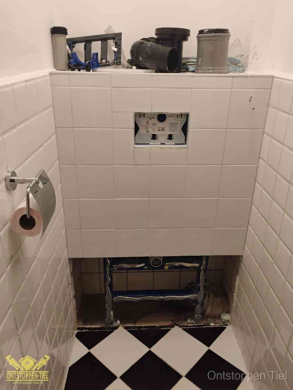 Een toiletruimte waar het hangtoilet en de inbouwreservoir-onderdelen zijn vrijgelegd voor onderhoud, periodiek nazicht voorkomt een wc-verstopping in Tiel