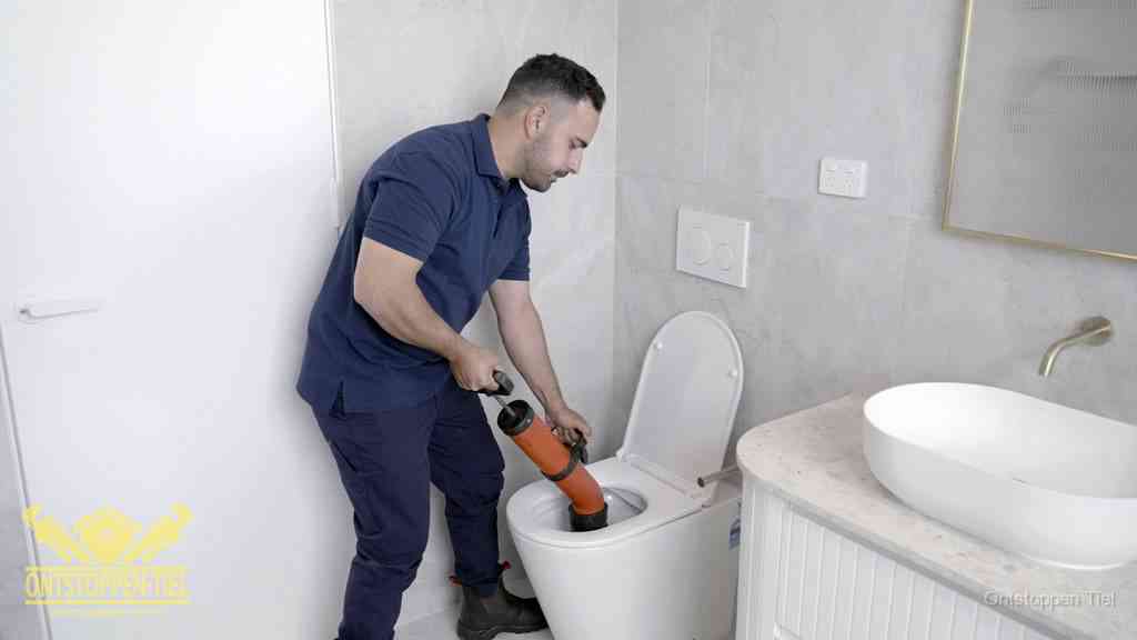 Een monteur gebruikt een handmatige perspomp (toiletontstopper) op een wandcloset tijdens het professioneel wc ontstoppen in Tiel